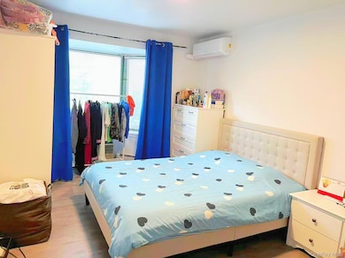 Bedroom featuring a wall mounted AC, light wood-style flooring, and a baseboard heating unit