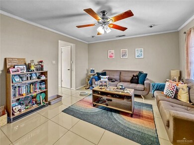 Living room featuring ceiling fan, ornamental molding, and tile patterned floors