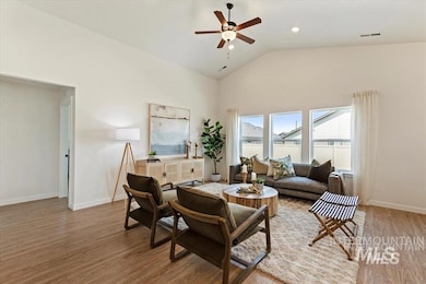 Living area featuring light wood-style floors, a ceiling fan, and high vaulted ceiling