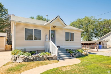 View of front of home with a shingled roof, a gate, and an outbuilding