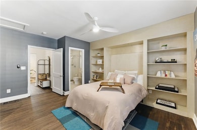 Bedroom 1 with wood finished floors, connected bathroom, a ceiling fan, and attic access