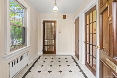 Entryway featuring inlaid floor details and radiator