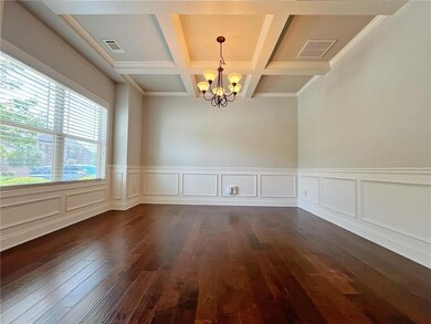 Empty room featuring a chandelier, dark wood-style flooring, coffered ceiling, beam ceiling, and a wainscoted wall