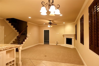 living room featuring crown molding, light carpet, light tile patterned floors, a fireplace with raised hearth, and stairs