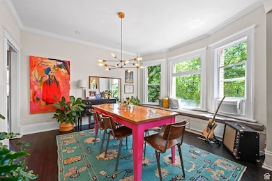 Dining room with ornamental molding, dark wood-style floors, and a chandelier
