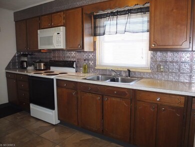 Applianced kitchen with tile floor, metal backspla