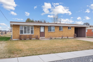 Single story home featuring brick siding, driveway, a front lawn, and a carport