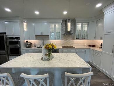 Kitchen featuring backsplash, a kitchen bar, light stone countertops, and recessed lighting