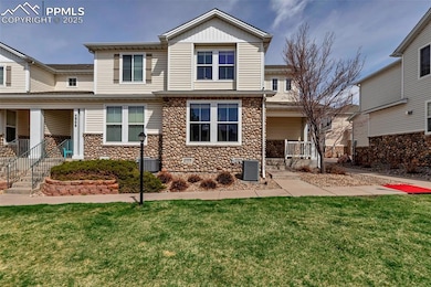 Rear view of property with stone siding, a lawn, a