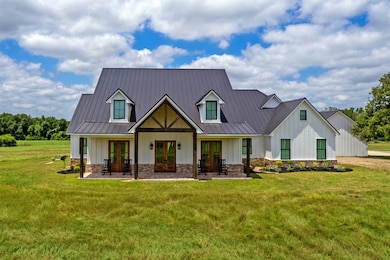 View of front of house featuring french doors, board and batten siding, a standing seam roof, and a front lawn
