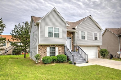 View of front of property featuring brick siding, driveway, a front yard, and an attached garage