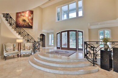 The foyer is beautifully enhanced with natural lighting that refracts through the double lead glass front doors and side lights. The wrought iron railing frame the three Travertine curved steps of the entry.
