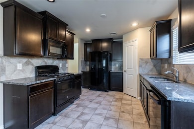Kitchen featuring black appliances, sink, and back