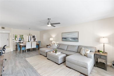 Living area with wood tiled floors, a chandelier, and a ceiling fan