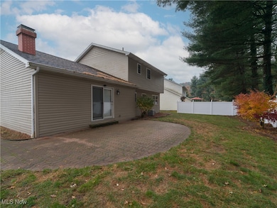 Rear view of house featuring a patio, roof with shingles, and a chimney