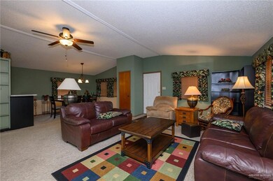 Carpeted living room featuring a ceiling fan, a textured ceiling, and lofted ceiling