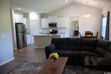 Living room with dark wood finished floors, a chandelier, vaulted ceiling, baseboards, and recessed lighting