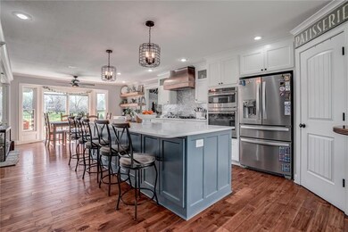 Kitchen featuring premium range hood, stainless steel appliances, a kitchen breakfast bar, white cabinets, and dark hardwood / wood-style flooring