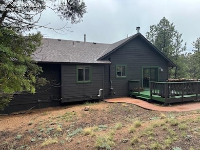 Rear view of house with a wooden deck and a shingled roof