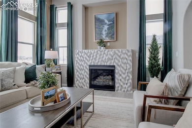 Living room with a tiled fireplace, plenty of natural light, and arched walkways