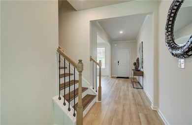 Entryway with light wood-style flooring, ornamental molding, and stairs