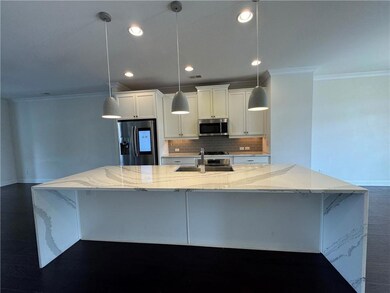 Kitchen with stainless steel appliances, crown molding, a spacious island, decorative backsplash, and white cabinets