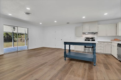 Kitchen featuring white cabinets, backsplash, appliances with stainless steel finishes, recessed lighting, and light wood-style flooring