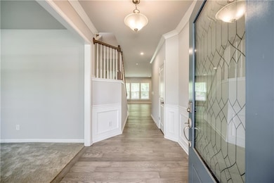 Entryway with light wood-type flooring, wainscoting, a barn door, a decorative wall, and crown molding