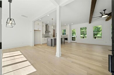 Unfurnished living room with beam ceiling, ceiling fan, and light wood-type flooring