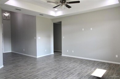 Unfurnished room featuring a tray ceiling, ceiling fan, dark wood-style flooring, baseboards, and a chandelier