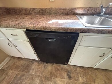Kitchen view of black dishwasher, a sink, and white cabinets