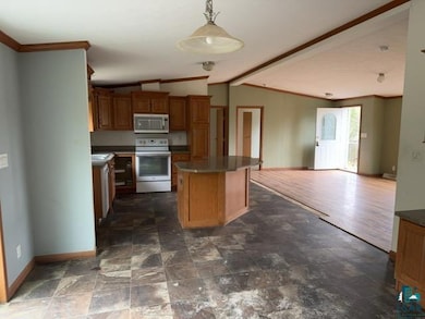 Kitchen with stainless steel microwave, white electric range oven, vaulted ceiling, crown molding, and baseboards
