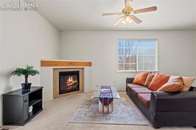 Carpeted living room featuring ceiling fan and a t