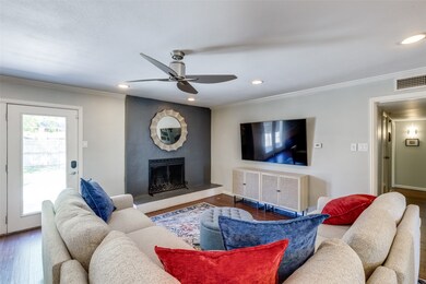 Living room with wood finished floors, a large fireplace, a ceiling fan, crown molding, and recessed lighting