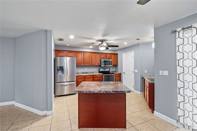 Kitchen with ceiling fan, a center island, appliances with stainless steel finishes, a textured ceiling, and light tile patterned floors