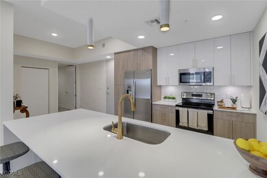 Kitchen showcasing sleek modern cabinetry, stainless steel appliances, and a waterfall island topped with elegant white quartz.