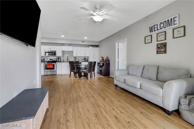 Living room featuring a ceiling fan, light wood-ty