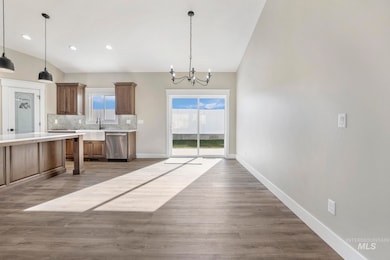 Kitchen with stainless steel dishwasher, a chandelier, light countertops, backsplash, and wood finished floors
