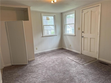 Unfurnished bedroom with carpet floors, wooden walls, and a textured ceiling