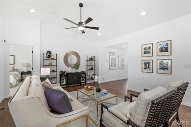 Living room with dark hardwood / wood-style flooring, ceiling fan, and lofted ceiling