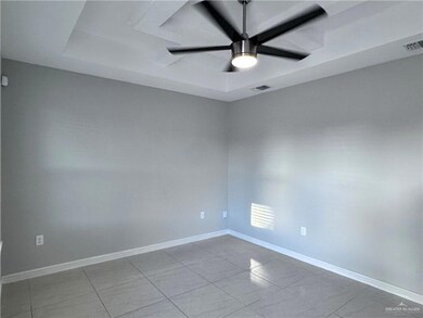 Empty room with baseboards, a ceiling fan, visible vents, and a raised ceiling