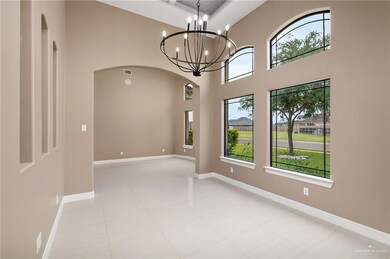Tiled empty room with a high ceiling and a notable chandelier