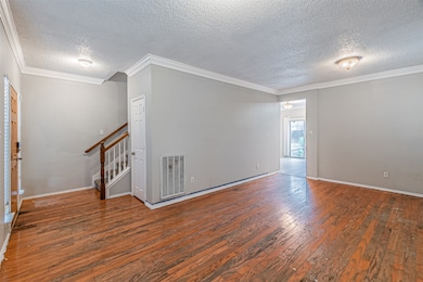 Spare room with crown molding, a textured ceiling, hardwood / wood-style flooring, and stairs