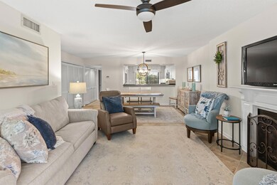 Living area with ceiling fan, a chandelier, and a fireplace with flush hearth