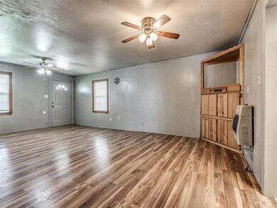 Unfurnished living room featuring ceiling fan, heating unit, light wood-style flooring, and a textured ceiling