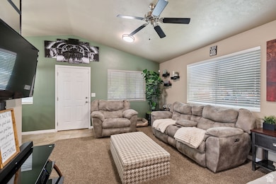 Living area with lofted ceiling, ceiling fan, and carpet floors