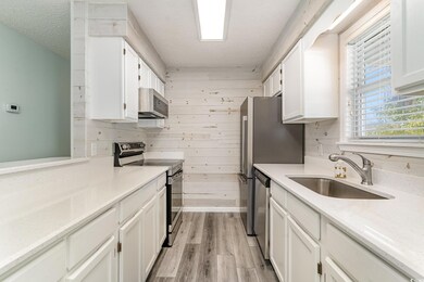 Kitchen featuring wooden walls, white cabinetry, s