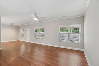 Unfurnished living room with plenty of natural light, wood finished floors, baseboards, ornamental molding, and a ceiling fan