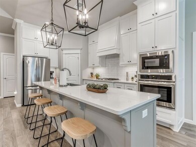 Kitchen with backsplash, an island with sink, ligh