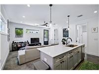 Kitchen with gray cabinetry, a sink, light counte